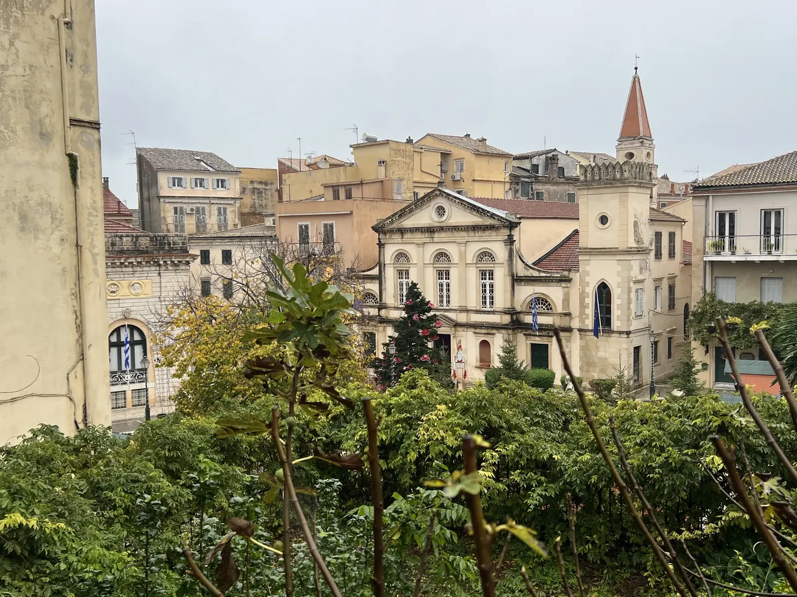 Corfu Old Town rooftops in rain, church spire, grey winter sky